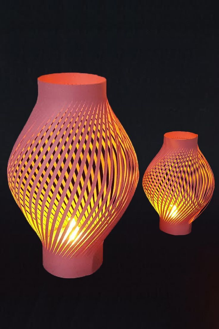 two lit vases sitting next to each other on a black surface with an intricate design