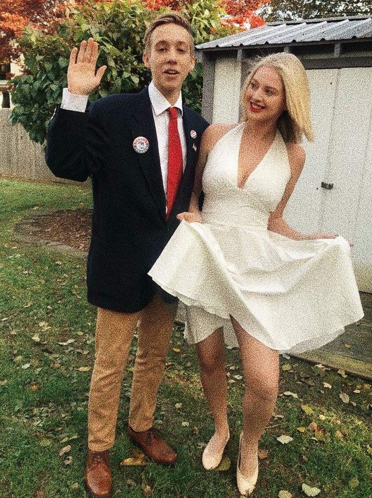 a man in a suit and tie standing next to a woman in a white dress