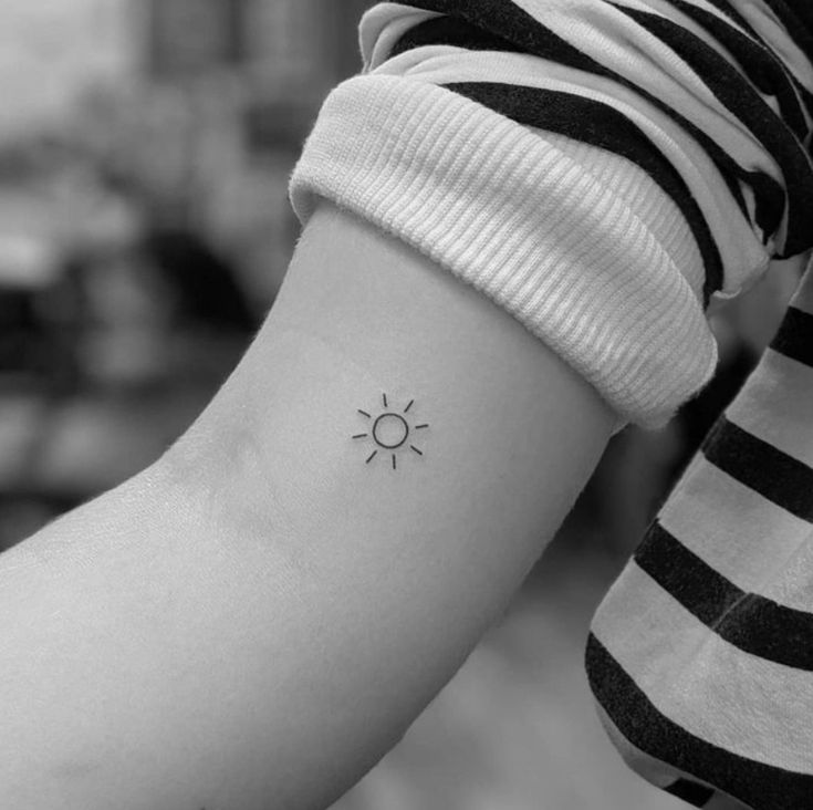 a woman's arm with a small sun tattoo on the left side of her arm