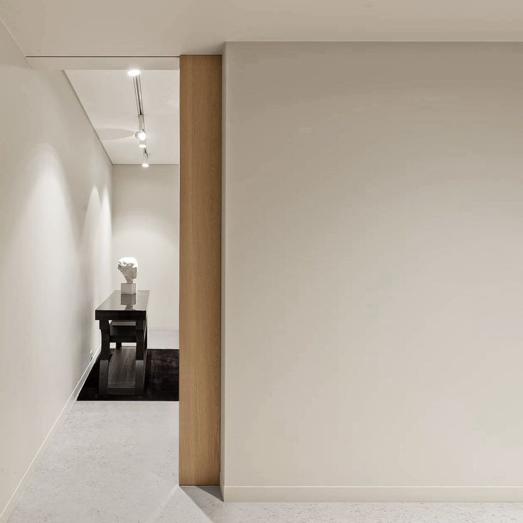 an empty white room with a table in the corner and lights on either side of the wall