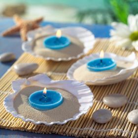 three blue candles sitting on top of plates with seashells and starfish in the background