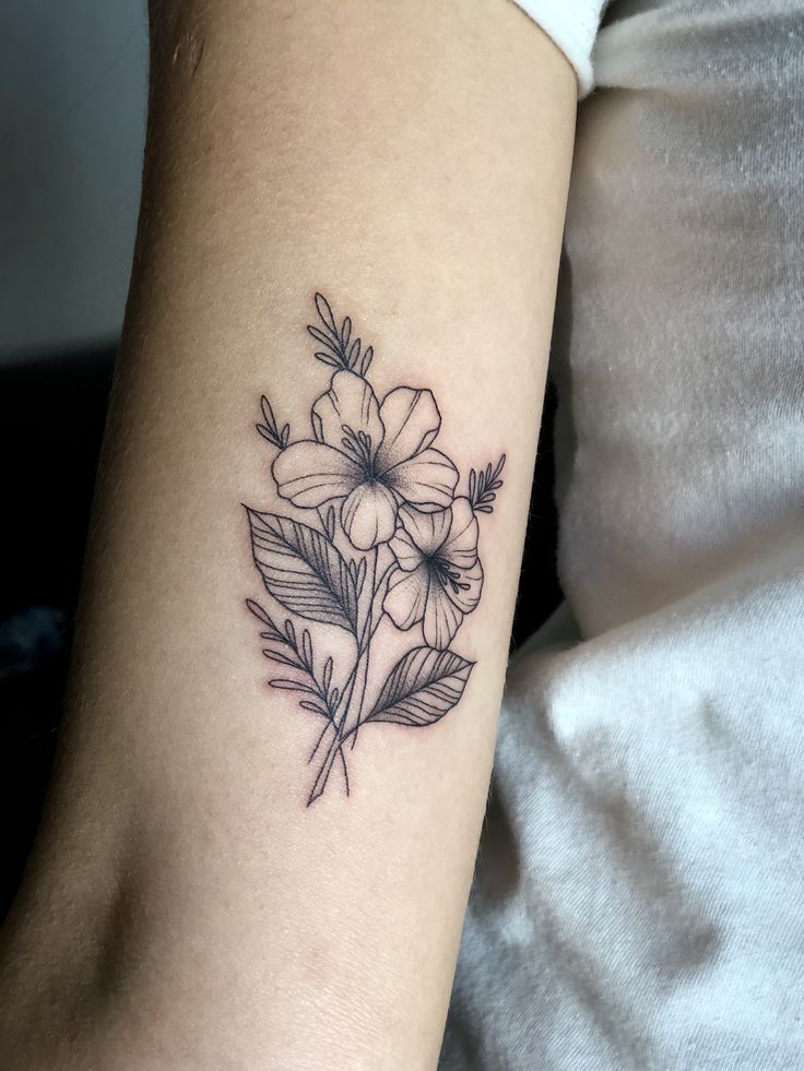 a woman's arm with a flower tattoo on the left side of her arm