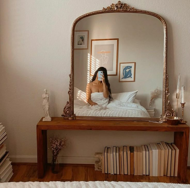 a woman sitting on a bed in front of a mirror