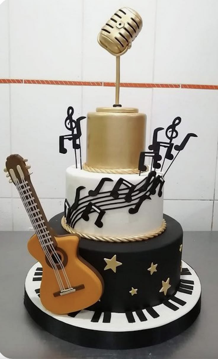 a three tiered cake with musical instruments and music notes on the top, as well as a guitar