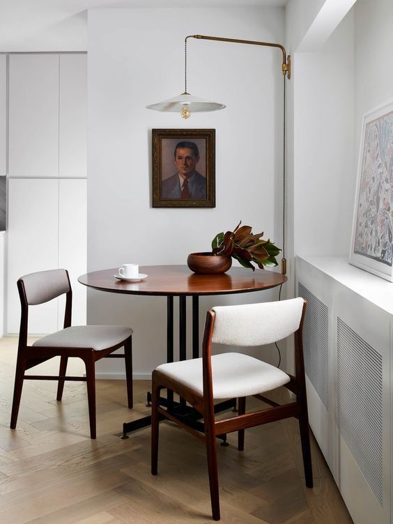 a dining room table with two chairs and a painting hanging on the wall above it