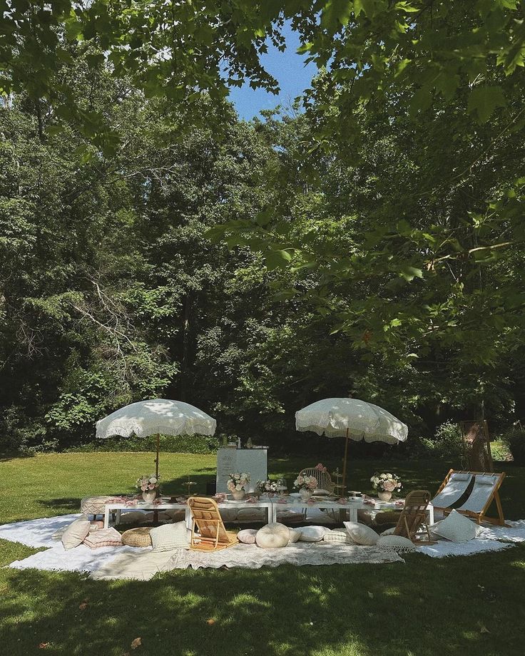 an outdoor area with lawn chairs and umbrellas in the shade, surrounded by lush green trees