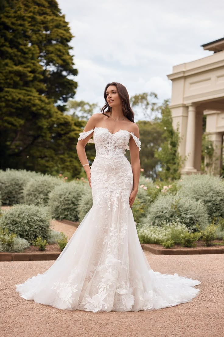 a woman in a wedding dress posing for the camera with her hands on her hips