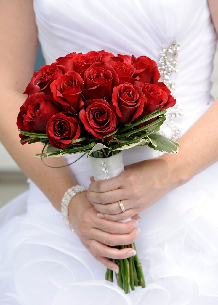 a bride holding a bouquet of red roses