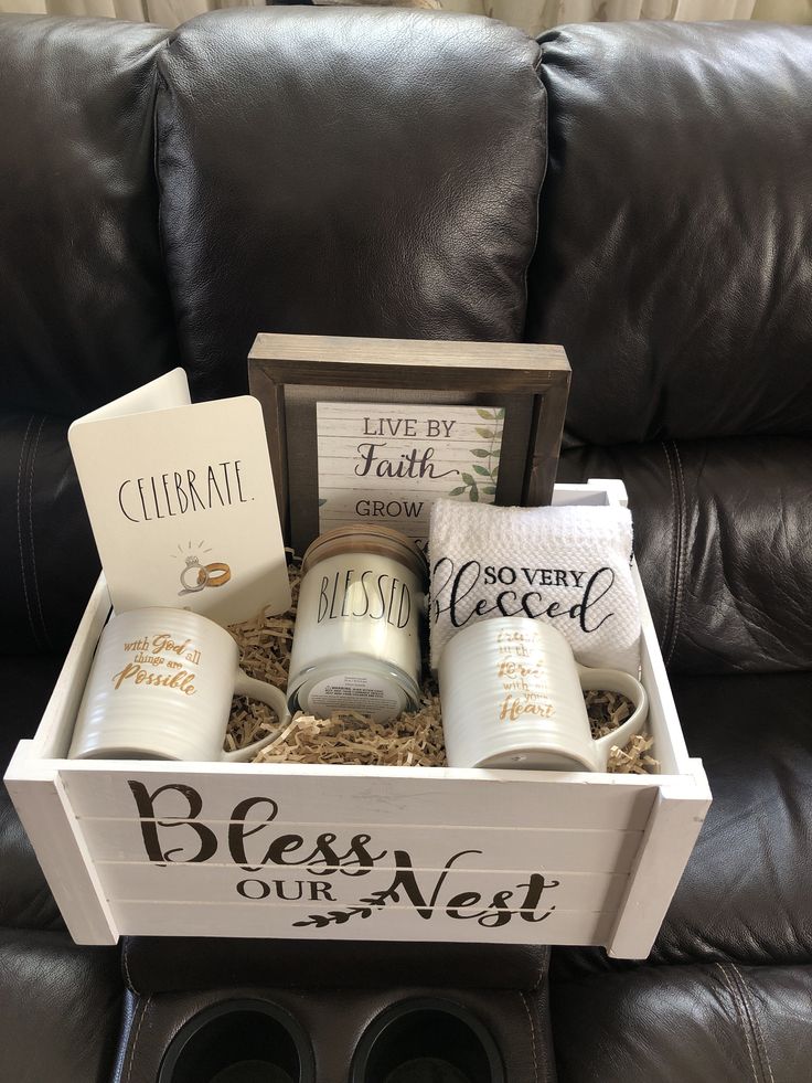 a box with coffee mugs and other items in it on a leather couch next to a pair of black shoes