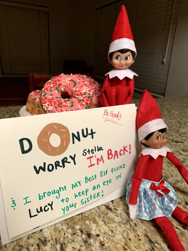 two elfs are sitting next to a donut sign