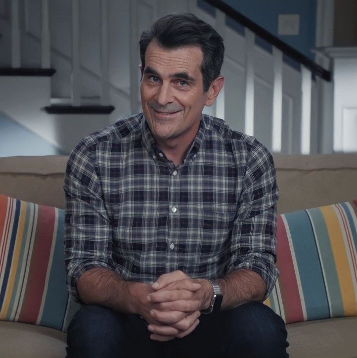 a man sitting on top of a couch with his hands folded in front of him