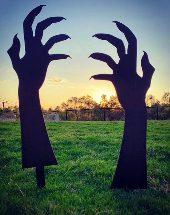 two silhouettes of hands reaching out to each other in a field at sunset with the sun setting behind them