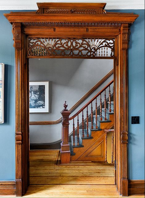 an ornate wooden door in the entry way to a house with blue walls and hardwood floors