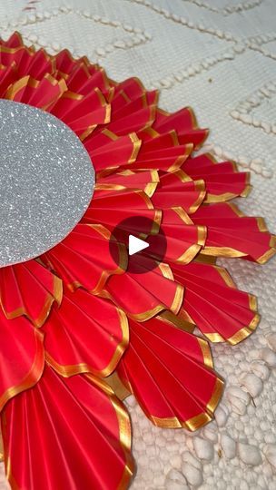 a close up of a red and gold flower on a white table cloth with a silver circle in the center