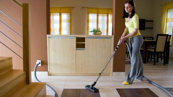 a woman is cleaning the floor with a vacuum