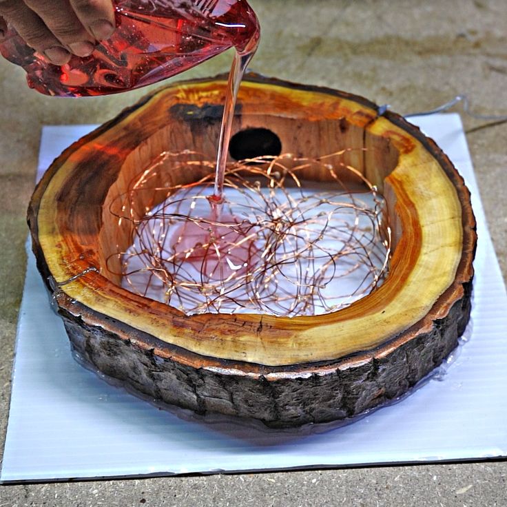 a person pouring something into a bowl on top of a wooden slab with wire wrapped around it