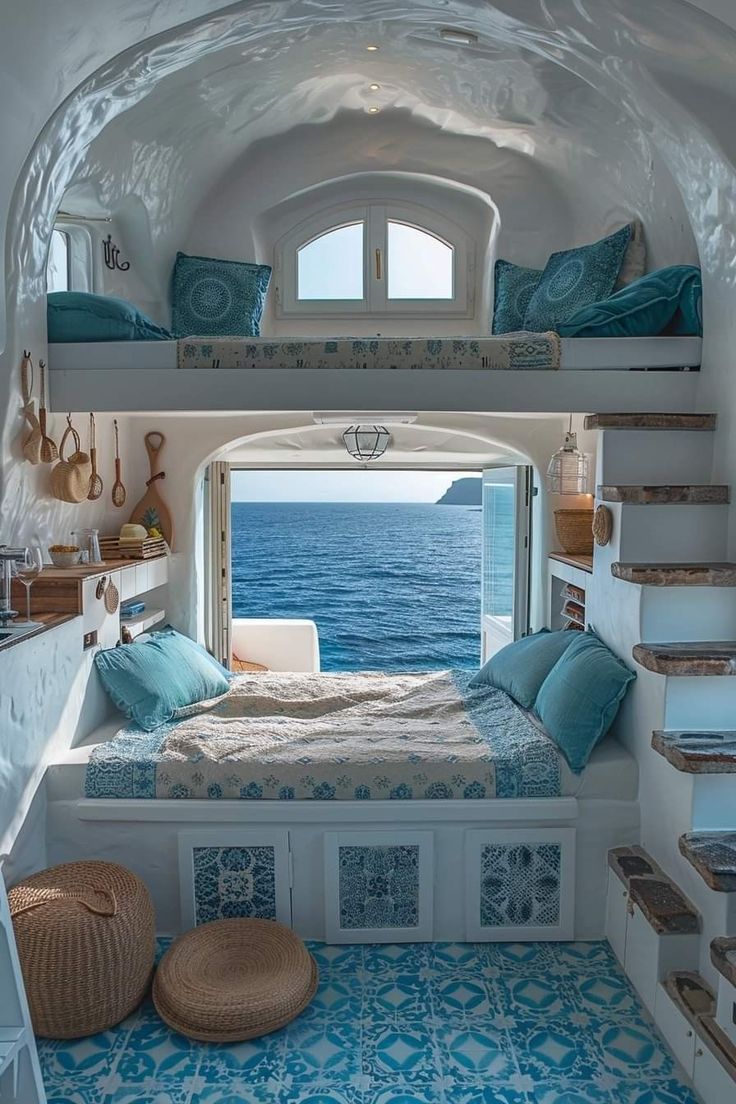 a bedroom with blue and white decor on the walls, stairs leading up to an ocean view