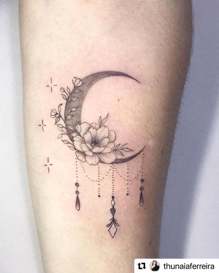 a woman's thigh with a crescent moon and flowers on it