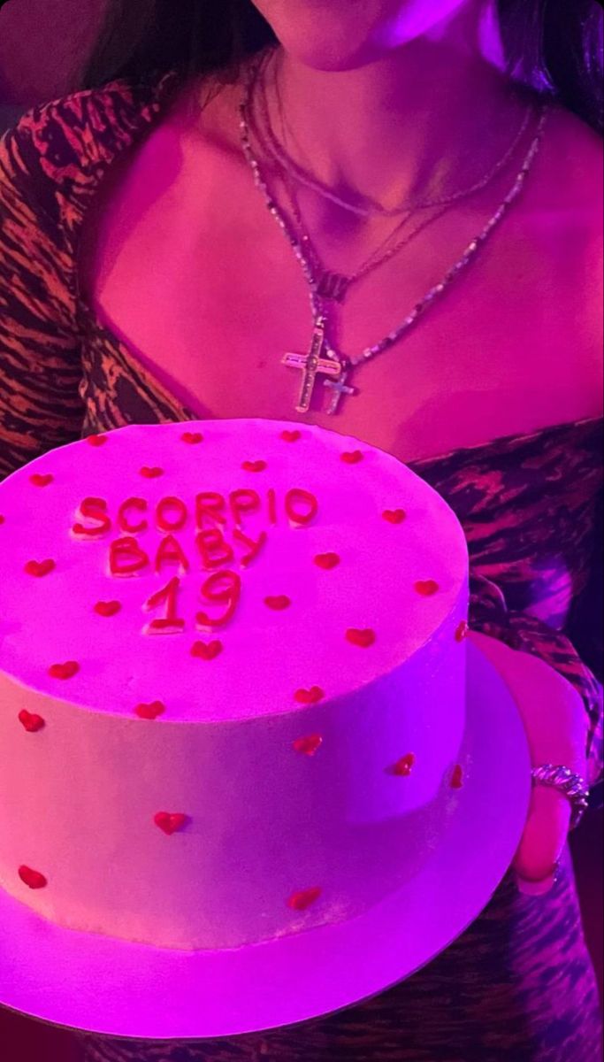 a woman holding a pink cake with red hearts on it and the words second birthday written in large letters