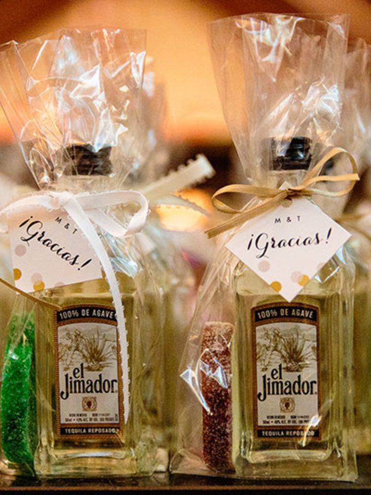 two bottles of liquor sitting on top of a wooden table next to bags filled with candy