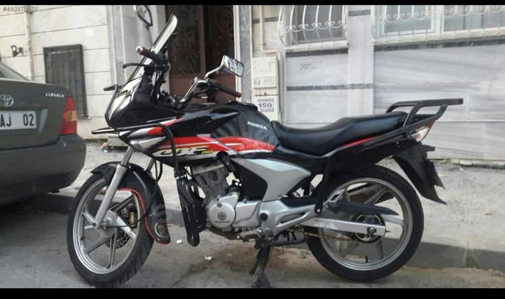 the motorcycle is parked on the side of the street next to the car in front of the building