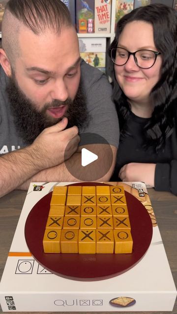 a man and woman looking at a cake on a table with the box in front of them