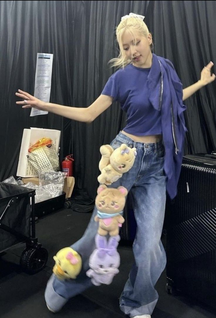 a woman is holding stuffed animals in her arms and posing for the camera with one hand