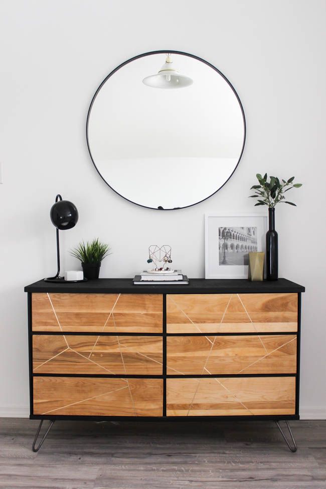 a wooden dresser topped with a round mirror