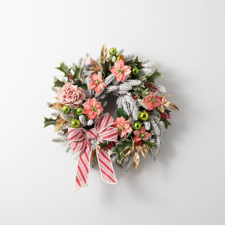 a christmas wreath with pink flowers and green leaves on a white background, hanging from the wall