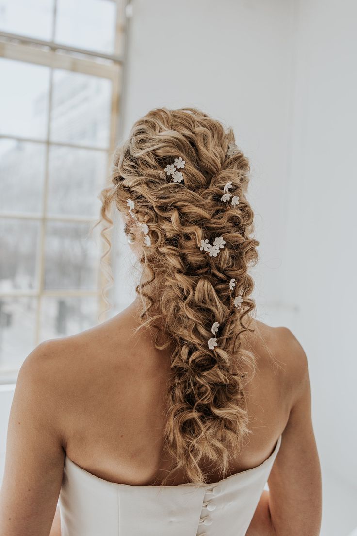 the back of a woman's head wearing a wedding dress with flowers in her hair