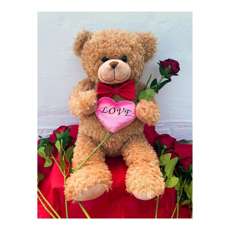 a teddy bear holding a heart with the word love written on it and roses in front