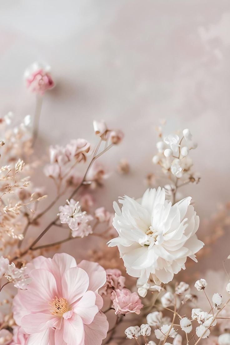 some pink and white flowers on a light colored tablecloth with watercolor paint in the background