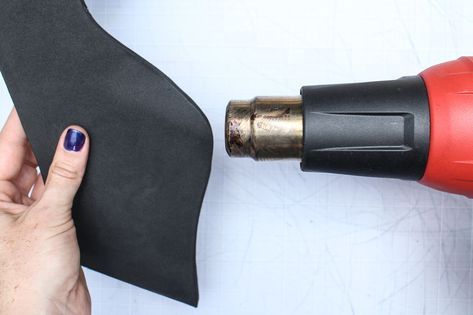 a person is using a drill to fix a piece of black fabric with a red tool