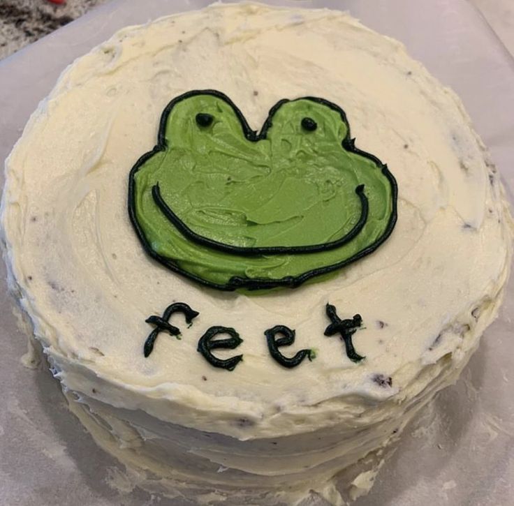 a cake with frosting that has a frog on it and the words feet spelled out