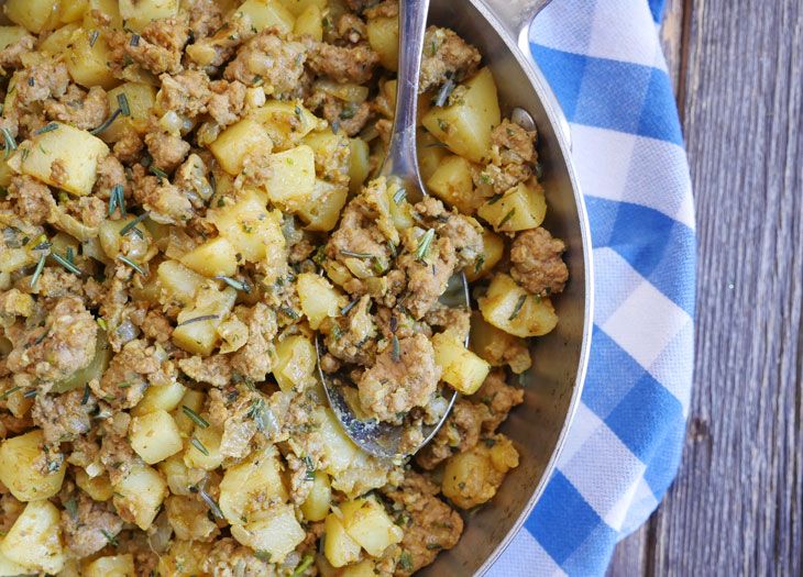 a bowl filled with meat and potatoes on top of a blue and white checkered cloth