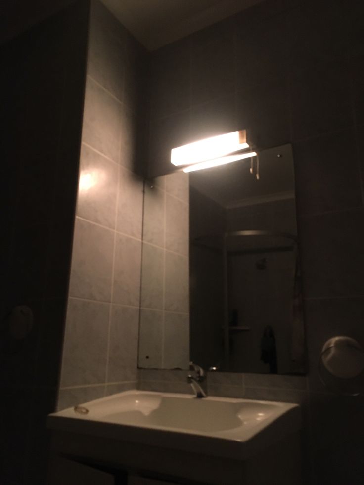 a bathroom sink sitting under a mirror next to a light