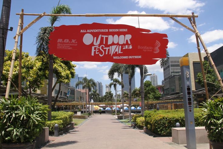 an outdoor festival sign in front of palm trees and other greenery on a sunny day