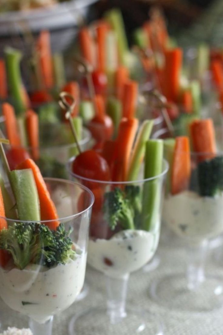 small cups filled with vegetables and dips on a white tablecloth covered table cloth