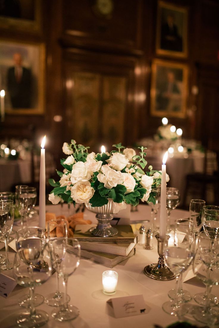 a table with candles, wine glasses and flowers on it is set for a formal dinner