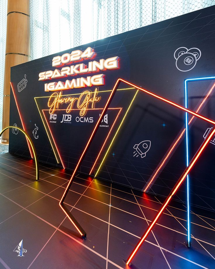 an event with neon lights on the floor and large black screen behind it that says sparkling gaming