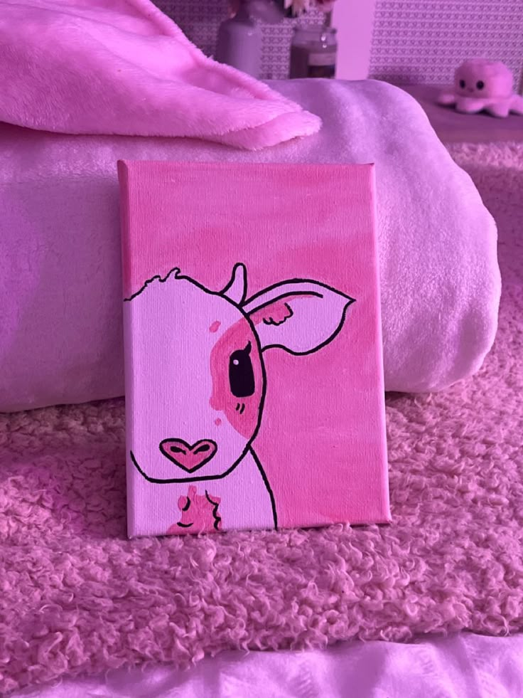 a painting of a cow on a pink background next to a bed with white sheets