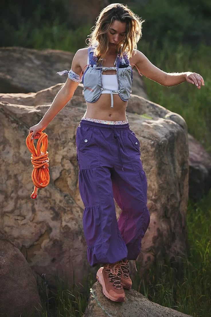 a woman standing on top of a rock next to grass