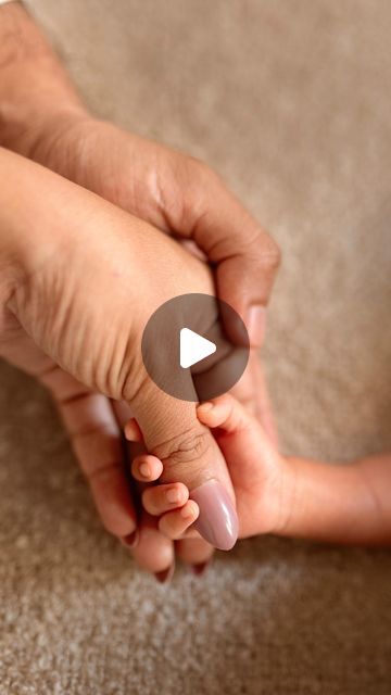 two hands holding each other over a carpeted area with a video play button in the middle