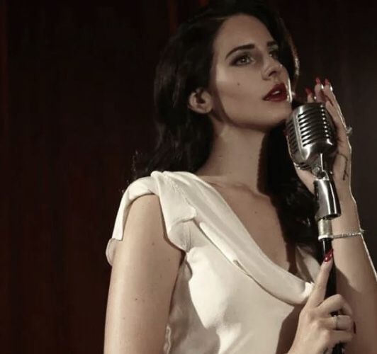 a woman in a white dress holding a microphone and posing for the camera with red lipstick on her lips