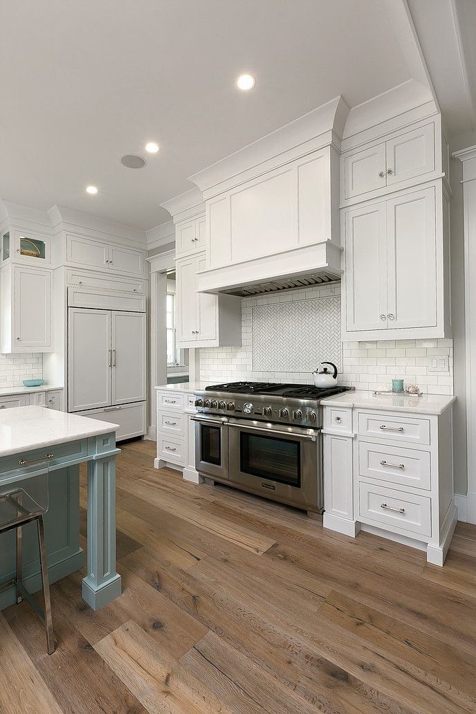 a kitchen with white cabinets and an island in the middle is shown, along with hardwood flooring