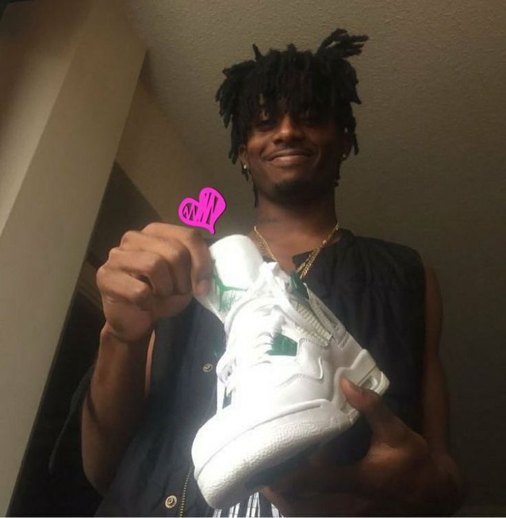 a man holding up a white sneaker with a pink sticker on it