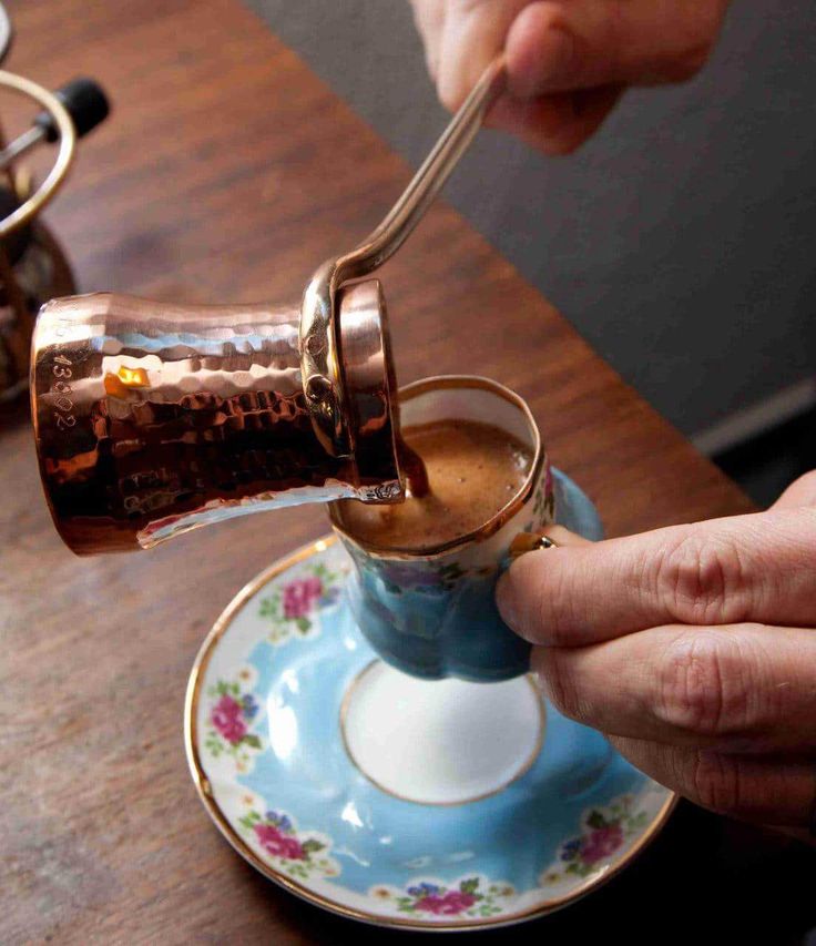 a person pouring coffee into a blue cup