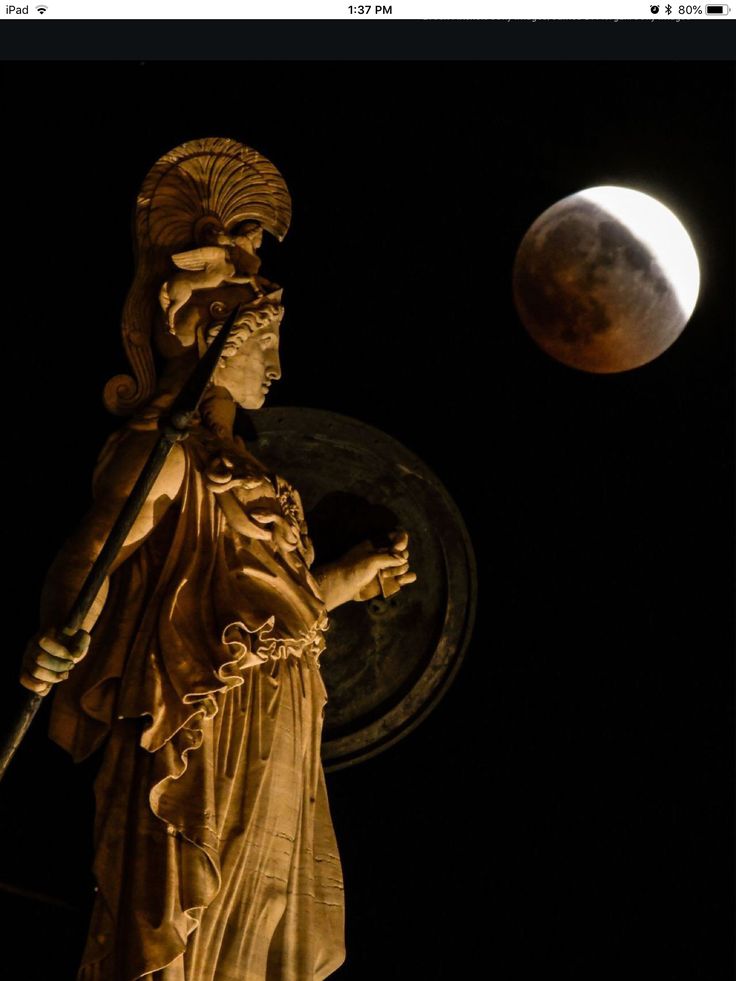 the statue is standing in front of the moon