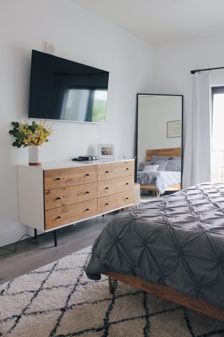 a bed room with a neatly made bed and a flat screen tv on the wall