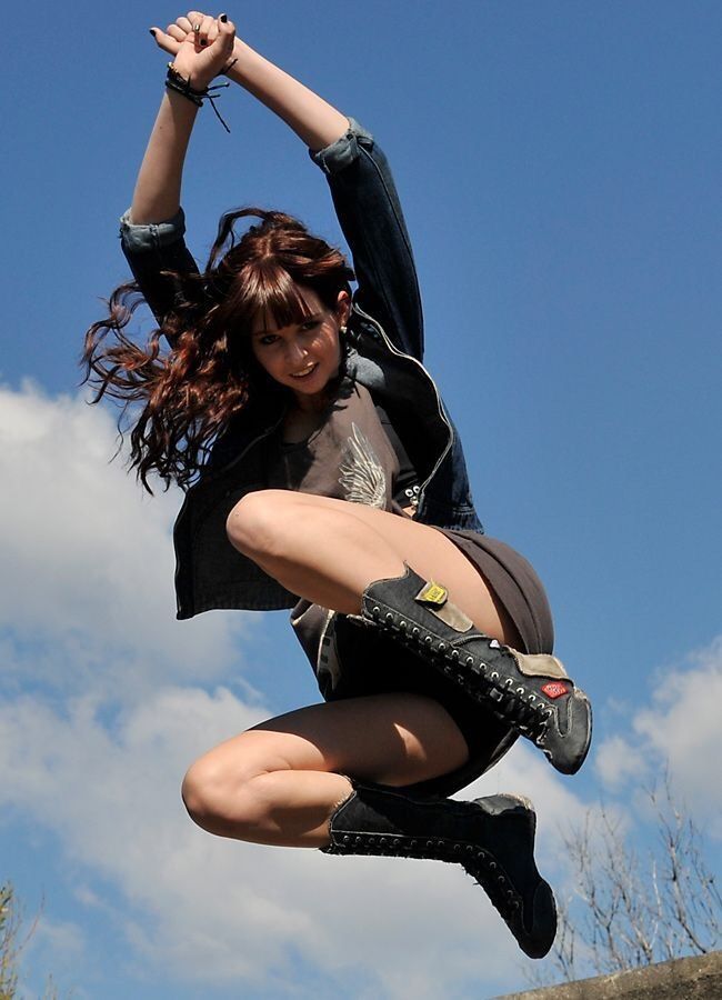 a woman is jumping in the air on a skateboard with her legs spread out